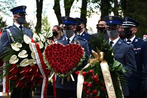 Policjanci trzymają wieniec w kształcie serca.