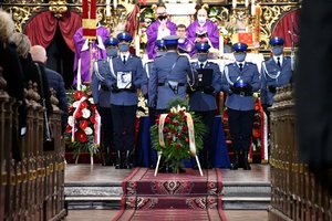 Umundurowani policjanci stoją przed ołtarzem. Trzymają fotografię zmarłego tragicznie Michała oraz czapkę.