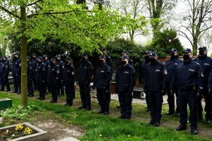 Umundurowani policjanci na cmentarzu, stoją w szeregu.