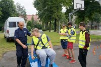 Dzieci testują symulator zderzeń pod czujnym okiem policjanta