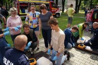 Policjant omawia zgromadzonym dzieciom zasady udzielania pierwszej pomocy przedmedycznej