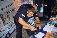 Dzieci podczas pikniku odwiedzają stoisko raciborskiej policji oglądają sprzęt i radiowóz