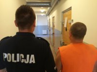 zdjęcie przedstawia policjanta i zatrzymanego mężczyznę tyłem