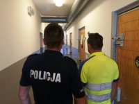 zdjęcie przedstawia policjanta i zatrzymanego mężczyznę tyłem