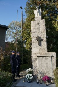 Stojący policjanci przed pomnikiem w Brzeziu