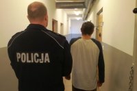 zdjęcie przedstawia funkcjonariusza policji oraz zatrzymanego sprawce kradzieży stojących tyłem