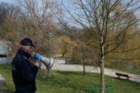 Raciborski policjant w rejonie parku przez urządzenie nagłaśniające przemawia do mieszkańców