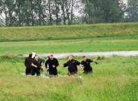 Raciborscy policjanci idą przez wysoką trawę z uratowaną załogą tratwy