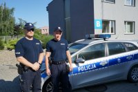 Policjanci z prewencji na tle radiowozu