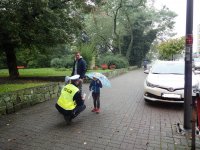 Policjant z raciborskiej drogówki rozdaje odblaski na ulicy