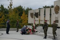 Delegacja służb mundurowych Policji i Straży Pożarnej składa wiązankę pod tablicą zabitych saperów