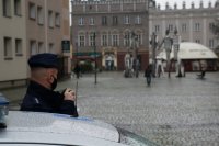 Policjant przez megafon w radiowozie ogłasza komunikat do mieszkańców związany z przestrzeganiem nakazu noszenia maseczek, zachowaniem dystansu społecznego