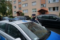 Policjant przez megafon w radiowozie ogłasza komunikat do mieszkańców związany z przestrzeganiem nakazu noszenia maseczek, zachowaniem dystansu społecznego