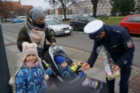 Policjant raciborskiej drogówki wręcza mamie z dzieckiem odblaski