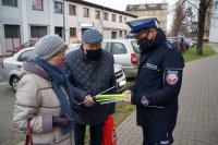 Policjant z drogówki wręcza seniorom odblaski