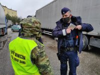 Policjant i Strażnik Graniczny na tle radiowozów policyjnych