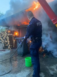 Policjant gasi pożar w budynku gospodarczym