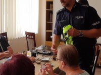 Policjant rozdaję gadzety wśród seniorów