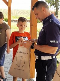 Policjant na spotkaniu z dziećmi mówi o bezpieczeństwie w czasie wakacji