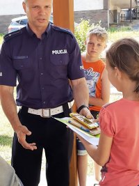 Policjant przekazuje dziewczynce upominek