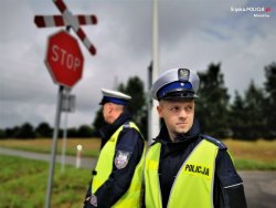 Policjant na tle znaku informującego o przejeżdzie kolejowym