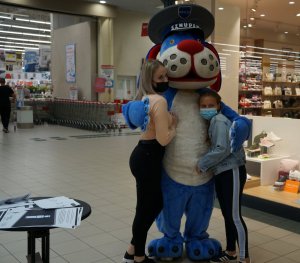 Policyjną maskotkę Sznupka obejmują dwie dziewczynki
