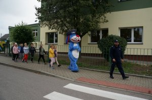 Policyjna maskotka Sznupek wraz z dziecmi idzie w kierunku przejścia dla pieszych