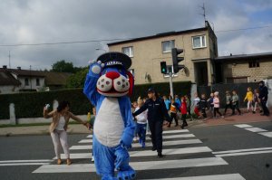 Raciborski policjant wspólnie z dziećmi i policyjną maskotką przechodzą przez przejście dla pieszych