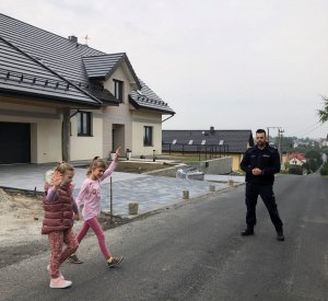 Dzieci pod czujnym okiem policjanta przechodzą przez drogę