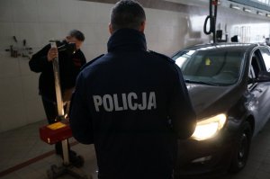 Diagnosta wspólnie z policjantem z drogówki kontroluje ustawienie świateł w samochodzie