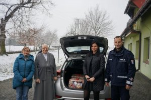 Komendant z siostrą zakonną i pracownicami policji na tle radiowozu