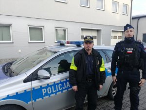 Policjant i Strażnik Miejski na tle radiowozu