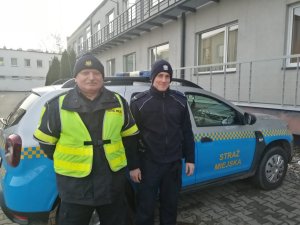 Policjant i Strażnik Miejski na tle radiowozu