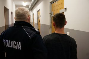 Zatrzymany sprawca pobicia stoi obok policjanta