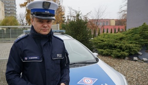 Policjant drogówki na tle radiowozu