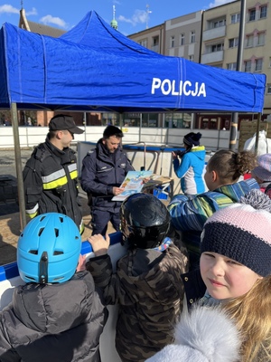 Policjant i strażak przy stoisku profilaktycznym dla dzieci