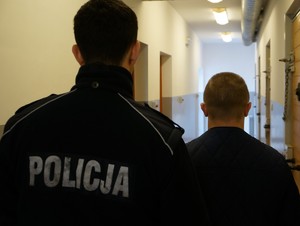 Zatrzymany mężczyzna stoi z policjantem za grożby karalne i posiadanie narkotyków