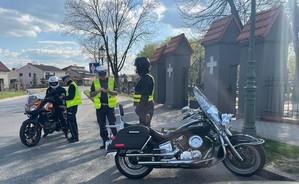 Policjanci z drogówki stoja przy zatrzymanym do kontroli drogowej motocyklistach