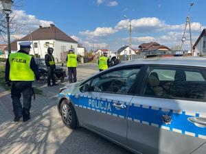 Policjanci z drogówki stoja przy zatrzymanym do kontroli drogowej motocykliście