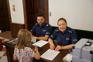 Policjanci z dzieckiem przy stoisku profilaktycznym