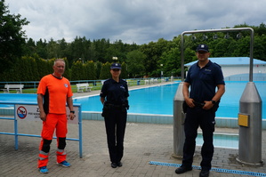 Wspólne zdjęcie policjantów i ratownika wodnego na tle basenu