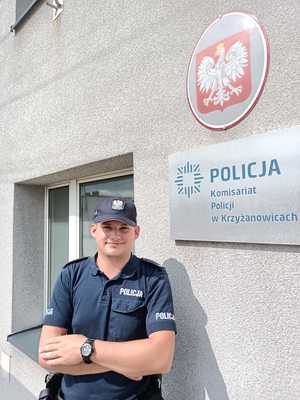 Policjant na tle Komisariatu Policji w Krzyżanowicach