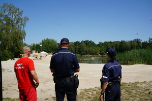 Ratownik wodny wspólnie z dzielnicowymi na tle zbiornika wodnego w Kuźni Raciborskiej podczas letniej kontroli