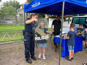 Policjanci na stoisku pokazują dzieciom sprzęt policyjny