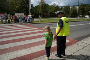 Policjant z dzieckiem przechodzi po pasach