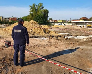 Policjant na tle budowy, gdzie został wykopany niewybuch