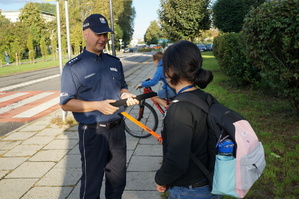 Policjant w rejonie szkoły wręcza dziecku odblask