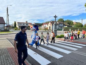 Policjant z dziećmi ćwiczy prawidłowe przejście przez pasy