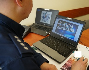 Widok policyjnych pagonów oraz komputera z napisem policja ostrzega