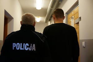 Policjant stoi z zatrzymanym, który chciał wręczyć łapówkę mundurowym